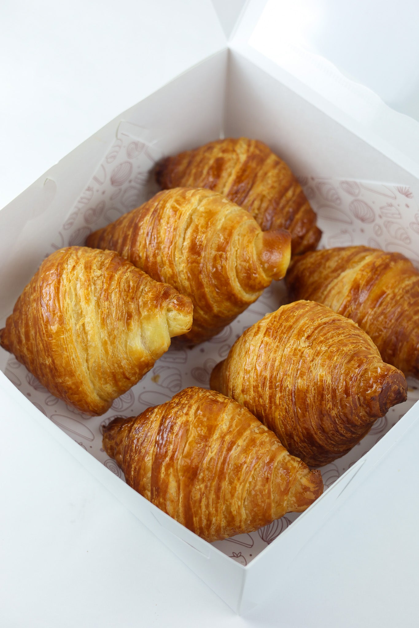 Golden brown butter croissant with flaky layers — available fresh daily at Shelíss Bakeshop