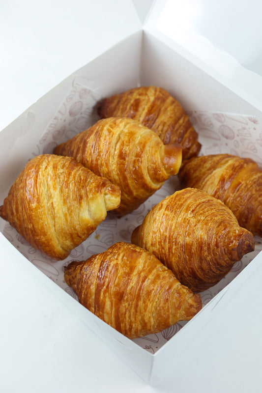 Golden brown butter croissant with flaky layers — available fresh daily at Shelíss Bakeshop